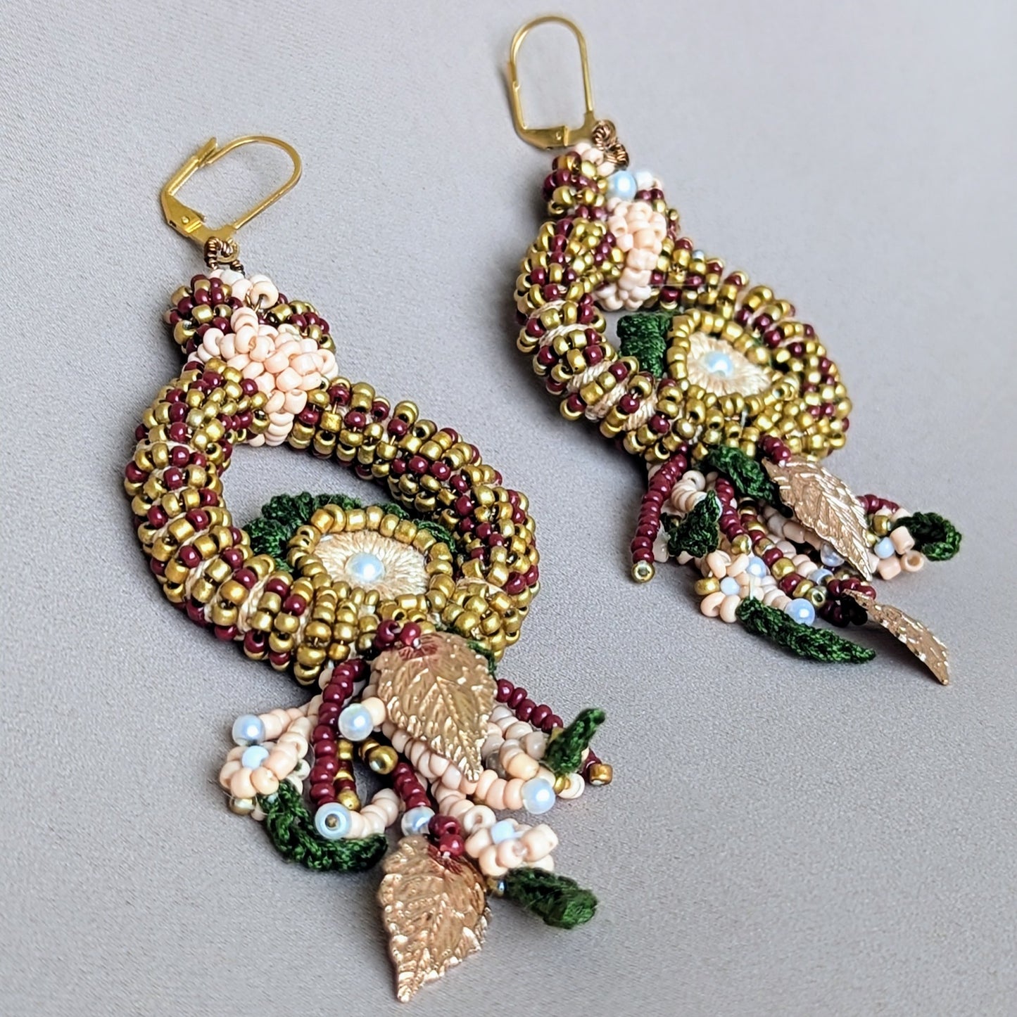 A stunning pair of one-of-a kind Indian bridal earrings exclusively available from Mayaani Jewellery, a sustainable UK brand. The earrings are adorned with intricate hand beaded designs in red, green and gold, arranges in a circular peacock inspired motif. They showcase exceptional craftsmanship ideal for a traditional Indian bridal look.