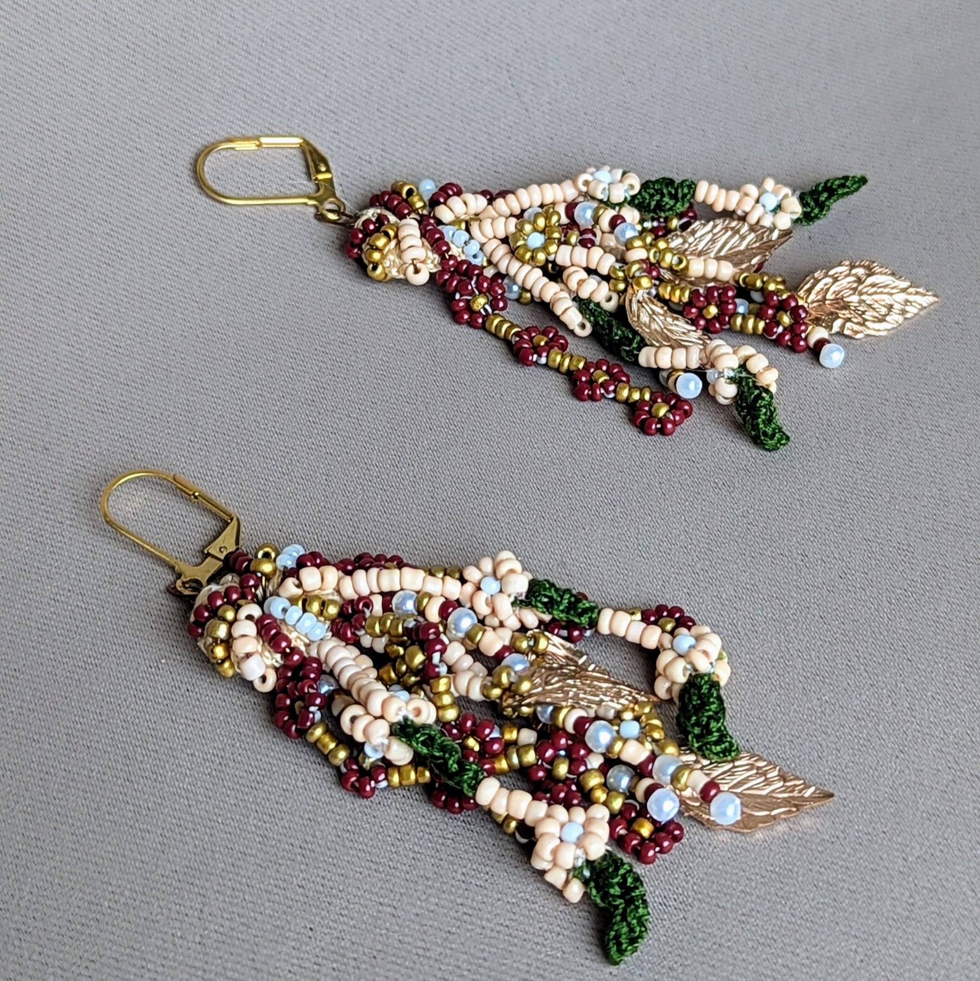 These meticulously crafted lightweight earrings blend comfort and elegance exclusive to sustainable UK brand Mayaani Jewellery. Inspired by Indian bridal traditions, they showcase vibrant red, green, and gold accents alongside delicate seed pearls. With hand-crochet and hand beaded strands rich in gold  leaf details, they celebrate India’s rich heritage.