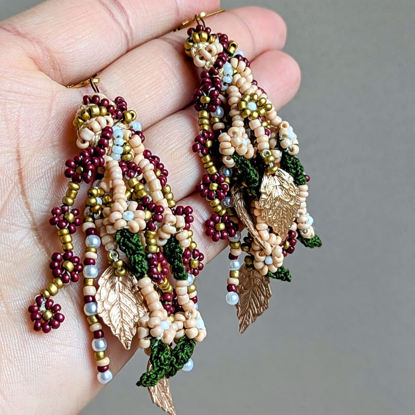 Crafted with precision, these unique lightweight earrings offer effortless elegance. Inspired by the beauty of Indian bridal fashion, they boast rich red, green, and gold tones, delicate pearls, and hand crochet and hand beaded details, finished with gold leaf accents that celebrate heritage. Exclusively at sustainable UK brand Mayaani Jewellery.