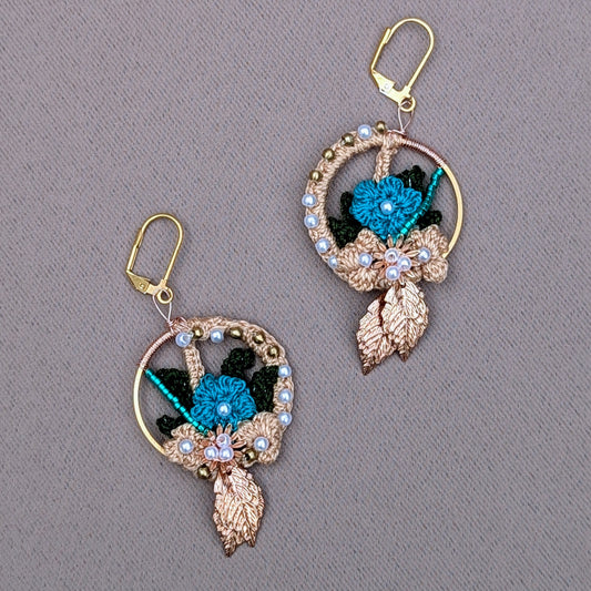 A unique artisan handcrafted pair of Indian-inspired earrings exclusive to the sustainable UK brand Mayaani Jewellery. Featuring artistically and intricately woven solid brass, seed pearl and blue beadwork with gold, blue and dark green crochet floral motifs. Lightweight, and comfortable for style you can enjoy for anything from your weddings and special occasions to everyday.