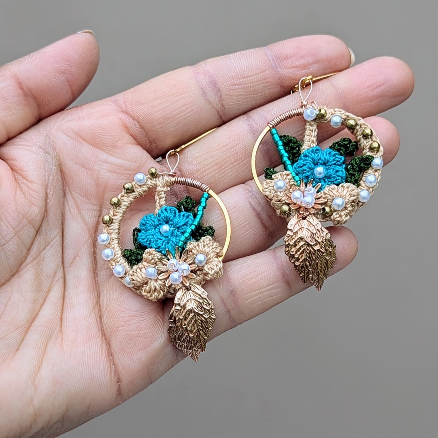 Delight in the exclusive design of these artisan-crafted Indian-inspired earrings by Mayaani Jewellery, a sustainable UK brand. With detailed solid brass weaving, seed pearls, and blue beads, they feature gold, blue, and dark green crochet floral motifs. Their lightweight and comfortable design makes them perfect for weddings, special occasions, or daily wear.