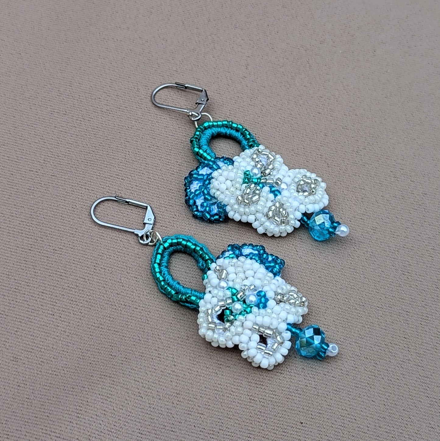 Presenting a gorgeous pair of handcrafted bridal earrings from the sustainable UK brand Mayaani Jewellery. Adorned with intricate hand crochet and floral motifs, these earrings feature contemporary stainless steel lever back clasps and high-quality upcycled Swarovski-style bicone beads, making them the perfect "something borrowed" for your special day.