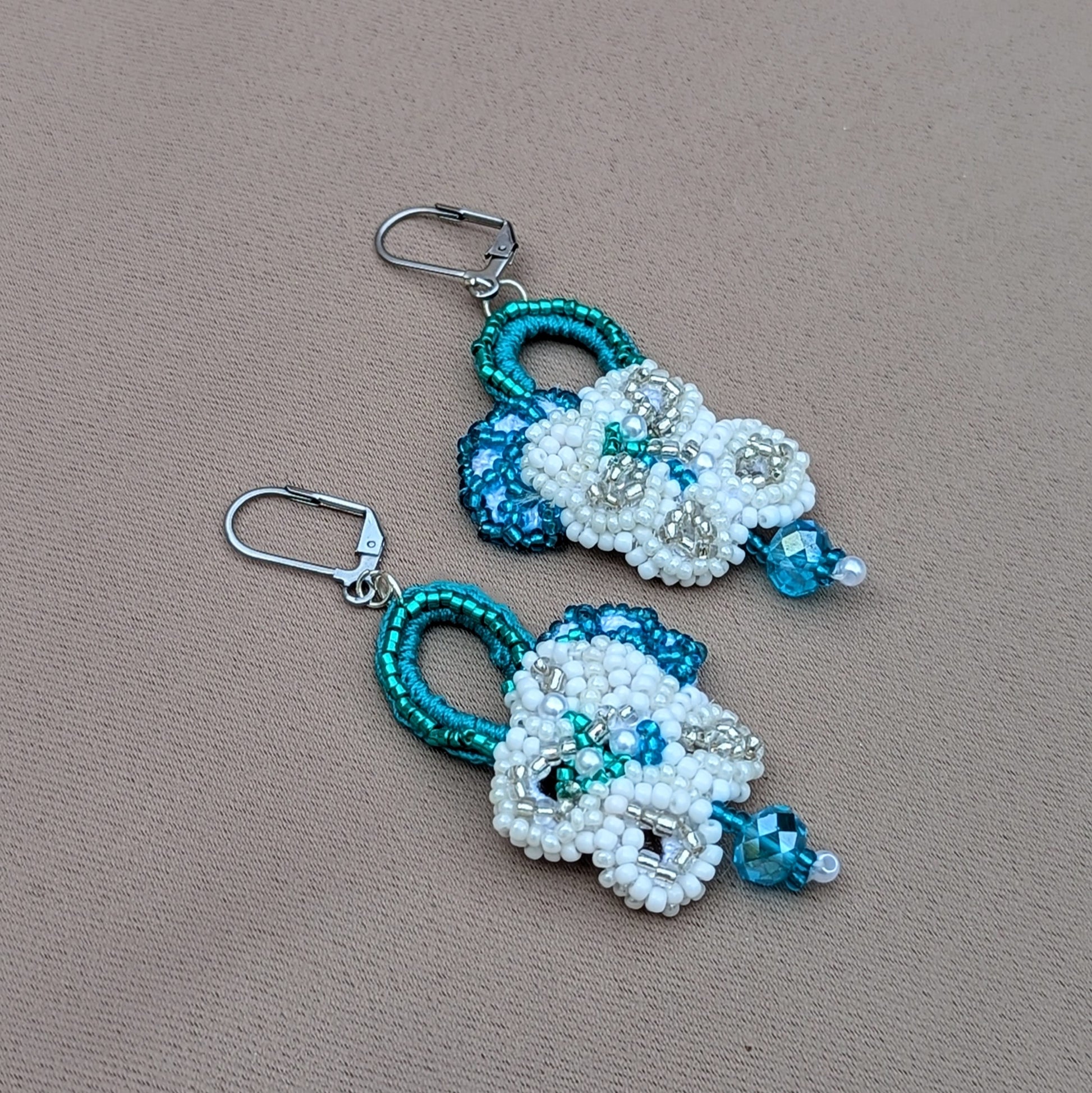 Presenting a gorgeous pair of handcrafted bridal earrings from the sustainable UK brand Mayaani Jewellery. Adorned with intricate hand crochet and floral motifs, these earrings feature contemporary stainless steel lever back clasps and high-quality upcycled Swarovski-style bicone beads, making them the perfect "something borrowed" for your special day.