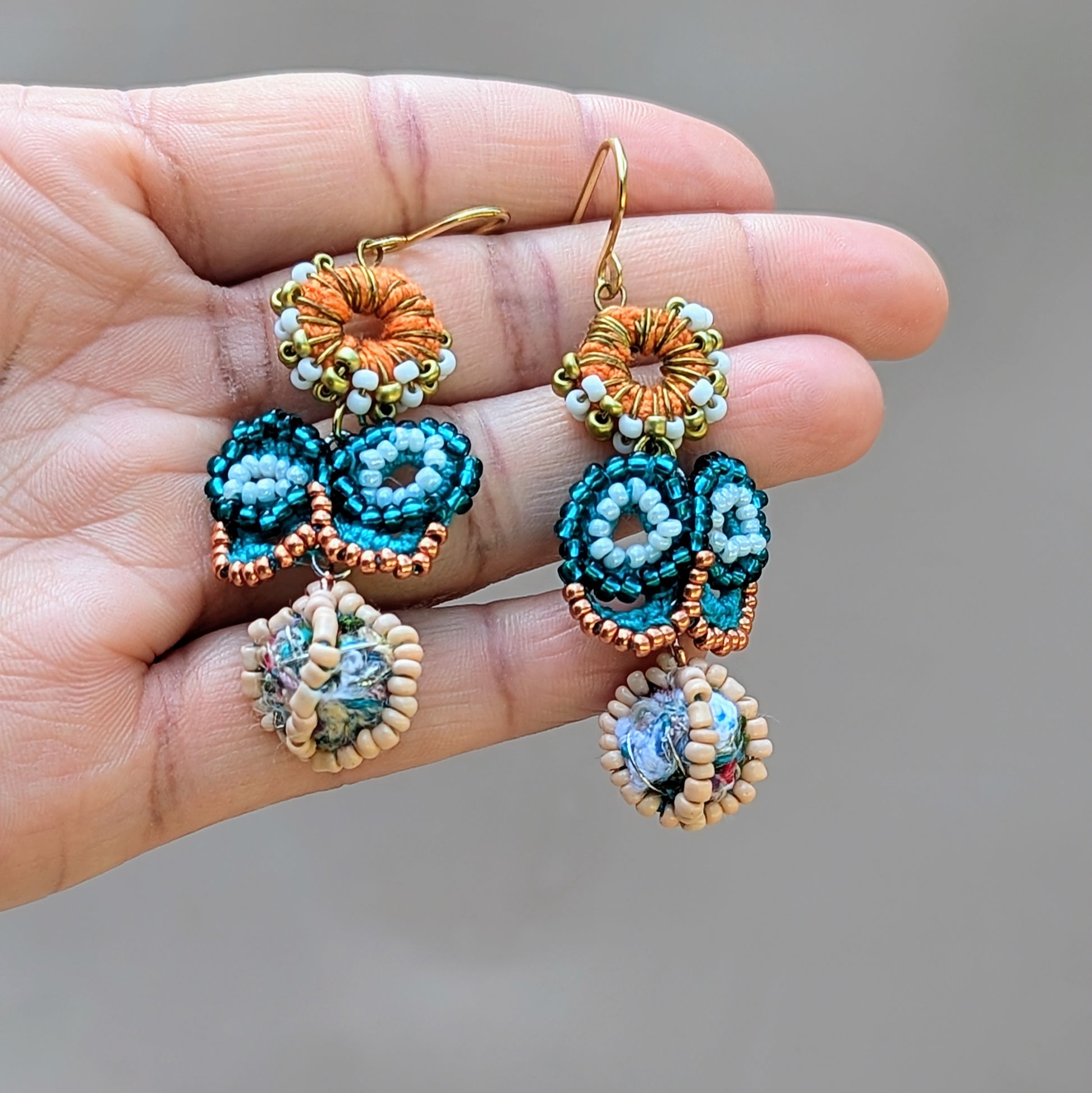 Beautiful blue butterfly earrings by sustainable brand Mayaani Jewellery UK, featuring a captivating scrap bead that transforms the design beneath a turquoise and rose gold seed bead butterfly. The Indian inspired earrings are topped with an orange crochet circle with white and gold seed beads, finished with gold-plated stainless steel hooks. Sustainable artistry meets traditional craftsmanship in this transformational pair.