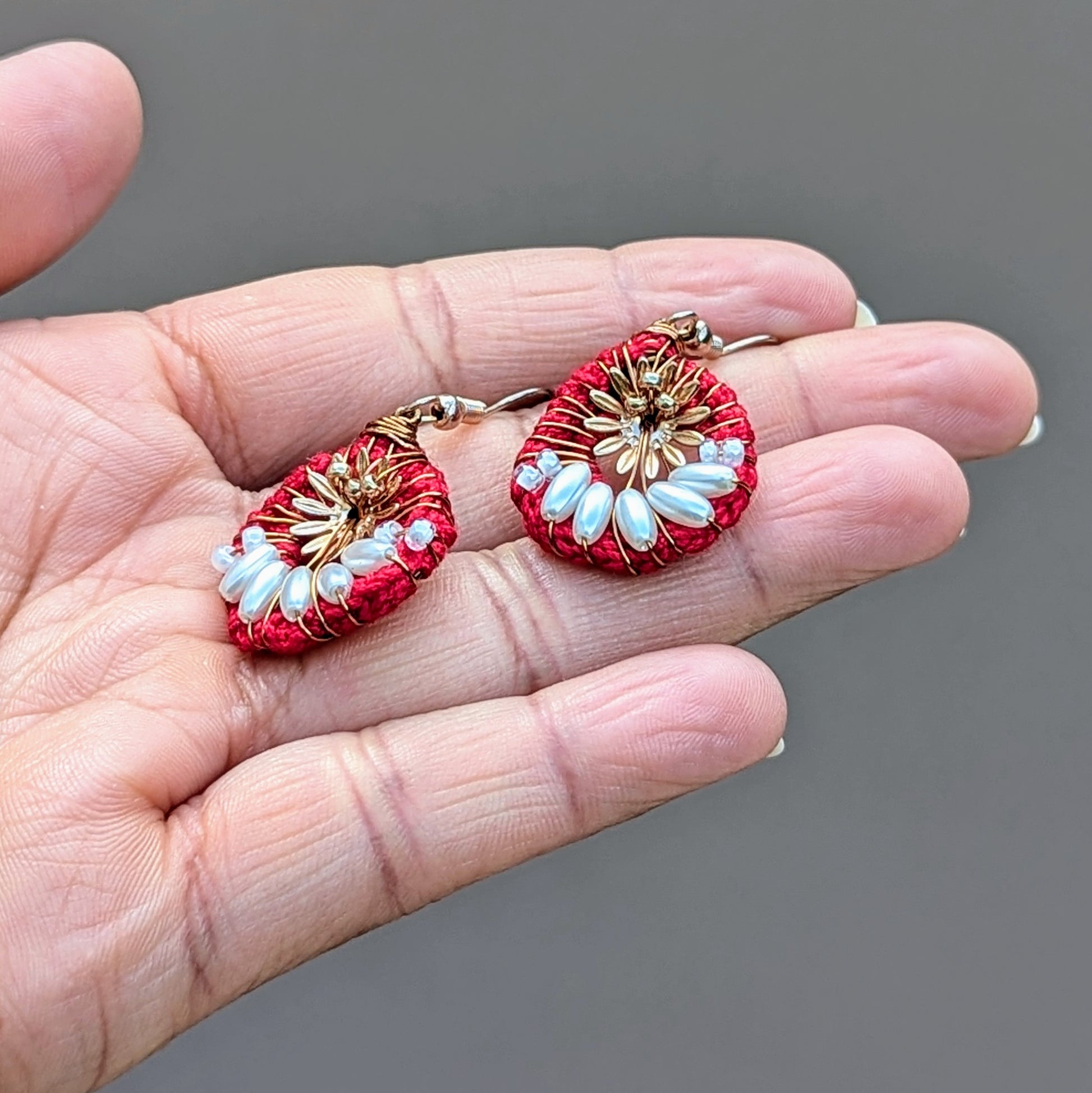 A one-of-a-kind handcrafted pair of teardrop earrings crafted from red, bronze, and seed pearls. This pair come with a majestic festive season inspired red, green, gold and white bracelet featuring high quality upcycled and new glass beads. Embrace the charm of lightweight modern designs infused with traditional craftsmanship, perfect for everything from special occasions to everyday.