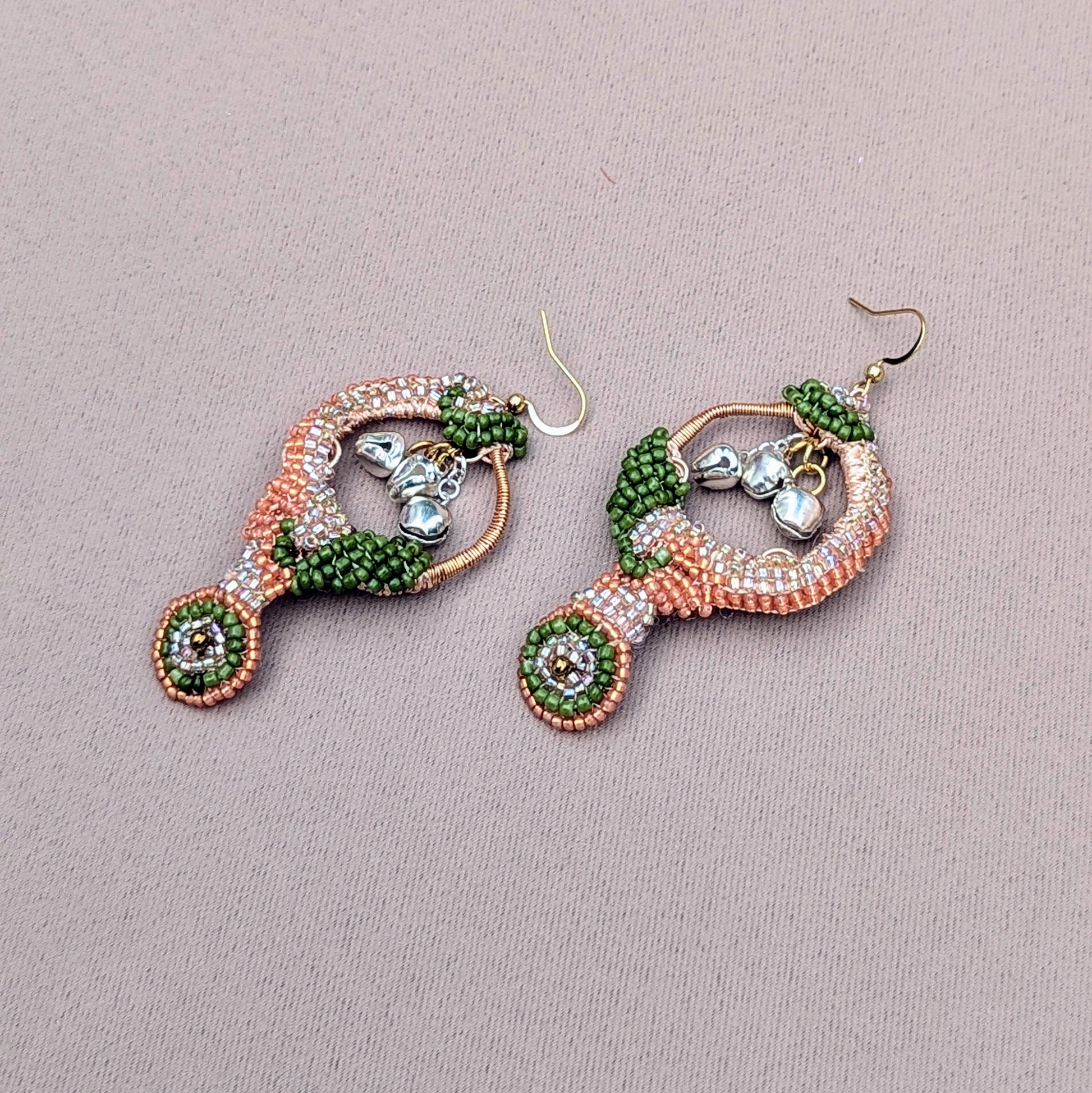 A pair of stunning, lightweight earrings with Indian-inspired design from the eco-conscious UK brand Mayaani Jewellery. Intended to inspire the dancer within, these exquisite earrings feature solid silver ghungroo bells that chime beautifully with each movement, echoing your classical Indian dance heritage. Adorned with opulent silver, peach, and green beads, and enhanced by hand crochet and wire wrapping, they are a perfect choice for weddings and other special events.