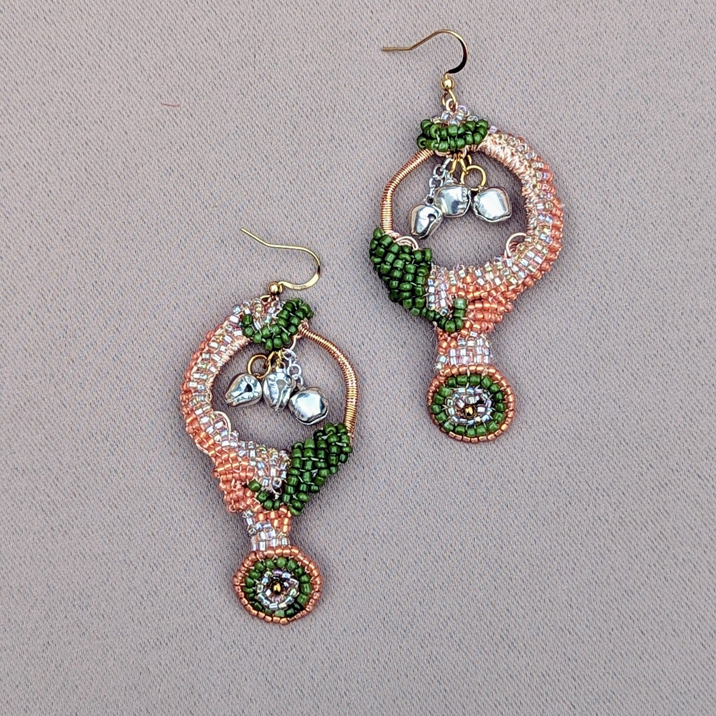 A pair of lightweight, Indian-inspired earrings by the sustainable UK brand Mayaani Jewellery, fit for a goddess. Designed to awaken your inner dancer, these enchanting earrings feature solid silver ghungroo bells that chime with each step, connecting you to your classical Indian dance heritage. With luxurious silver, peach, and green beads, along with hand crochet and wire wrapping, they make a perfect, resplendent accessory for any wedding or special event.