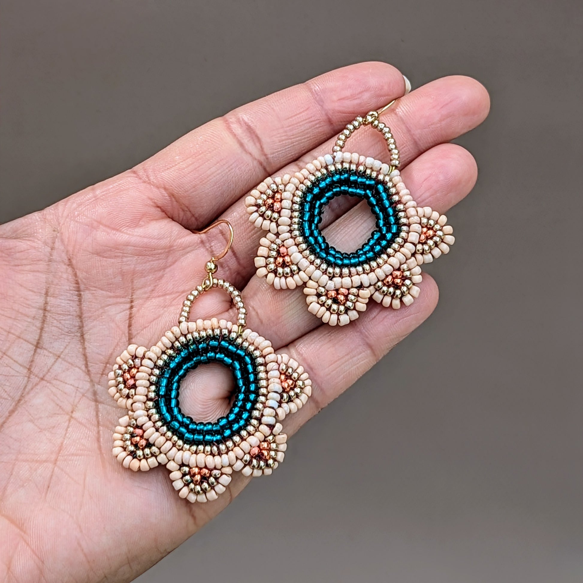 ntroducing a distinctive pair of bridal and special occasion earrings from Mayaani Jewellery, a sustainable handcrafted luxury Indian brand. These earrings showcase exquisite hand beadwork adorned with emerald green and peach accents in a circular floral design. While they are part of a matching bridal set, their versatility allows them to shine on their own, seamlessly blending traditional craftsmanship with contemporary elegance.