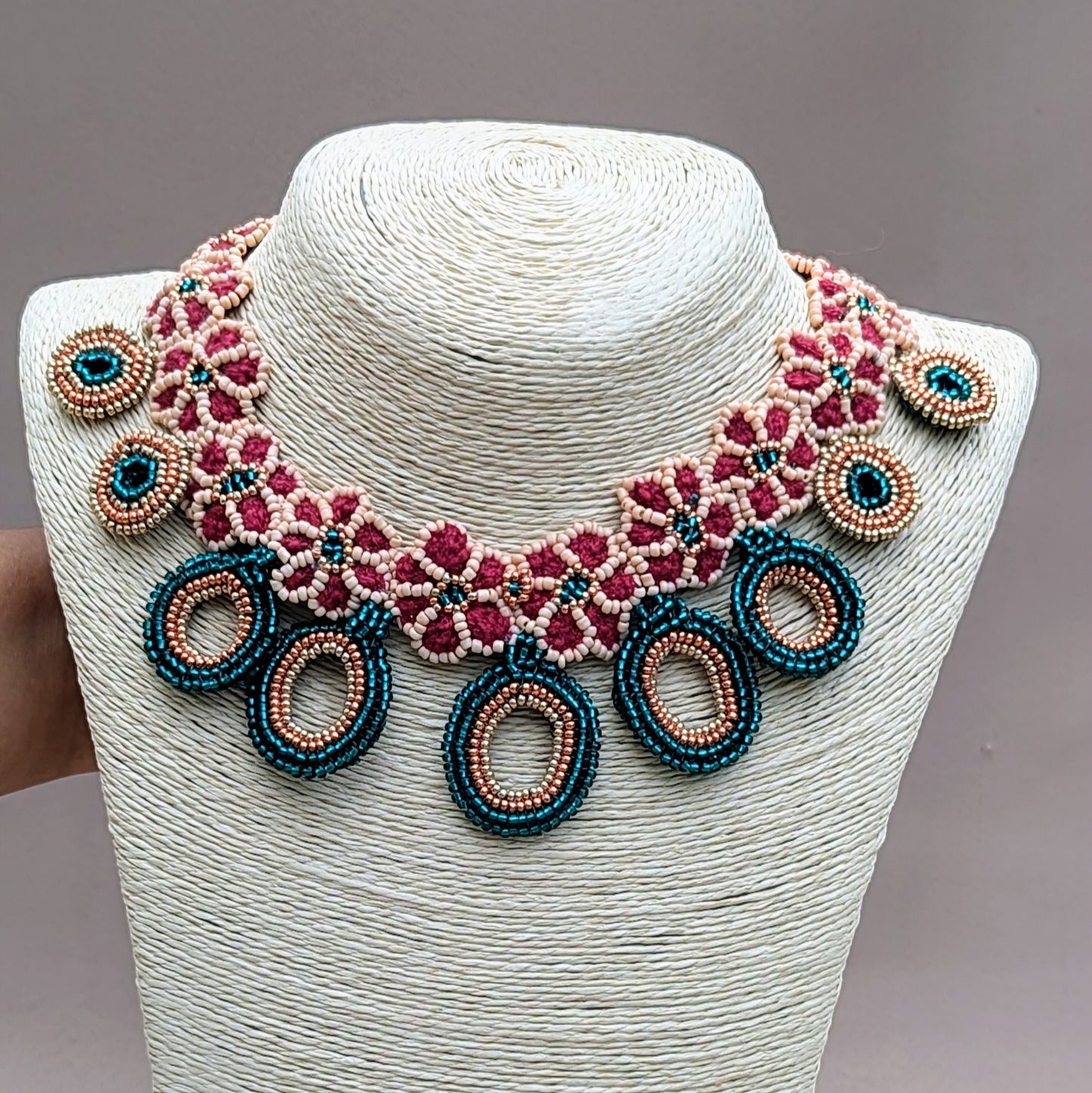 Exclusive handcrafted necklace by sustainable UK Indian wedding & occasion brand Mayaani Jewellery. Inspired by Indian bridal traditions, the design blends red hand-crocheted elements with intricate beadwork in shade of emerald green and peach, accented with rose gold and gold beads. Circular bead pendants and floral motifs add a modern twist to this classic Indian aesthetic making this a stunning statement piece.