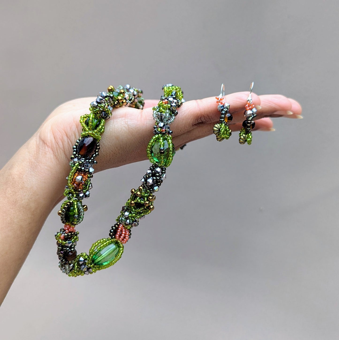 Celebrate the beauty of nature’s seasons with this artisan handcrafted beaded choker necklace from Mayaani Jewellery, a sustainable Indian UK brand. Immerse yourself in a bold palette of greens and browns, featuring a blend of new and high-quality upcycled glass seed beads that are expertly woven and artistically combined. This statement necklace is perfect for adding a touch of eco-conscious sophistication to any ensemble and includes a coordinating pair of short drop earrings.