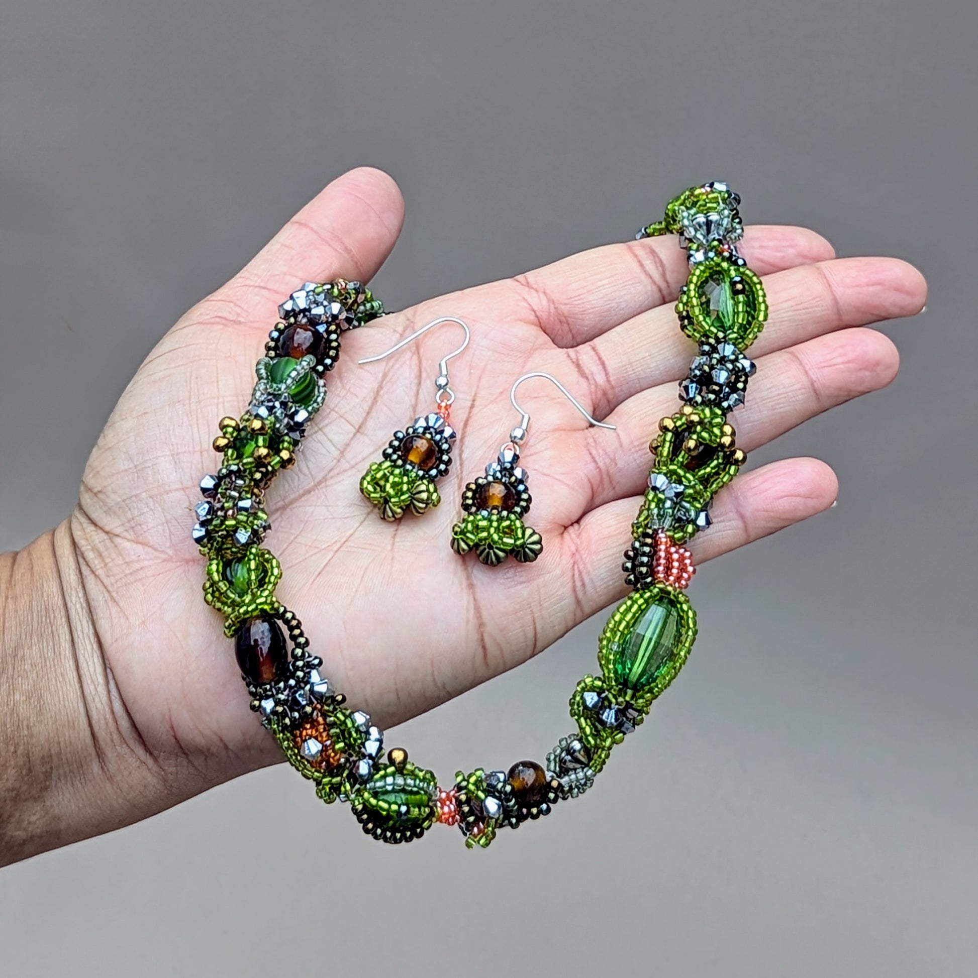 Experience the beauty of nature’s many seasons with this unique artisan handcrafted beaded choker necklace from sustainable Indian UK brand Mayaani Jewellery. Rich in greens and browns, this striking piece combines new and high-quality upcycled glass seed beads, meticulously woven and artistically intertwined. It’s the perfect eco-conscious statement accessory for any outfit, complete with a matching pair of short drop earrings.