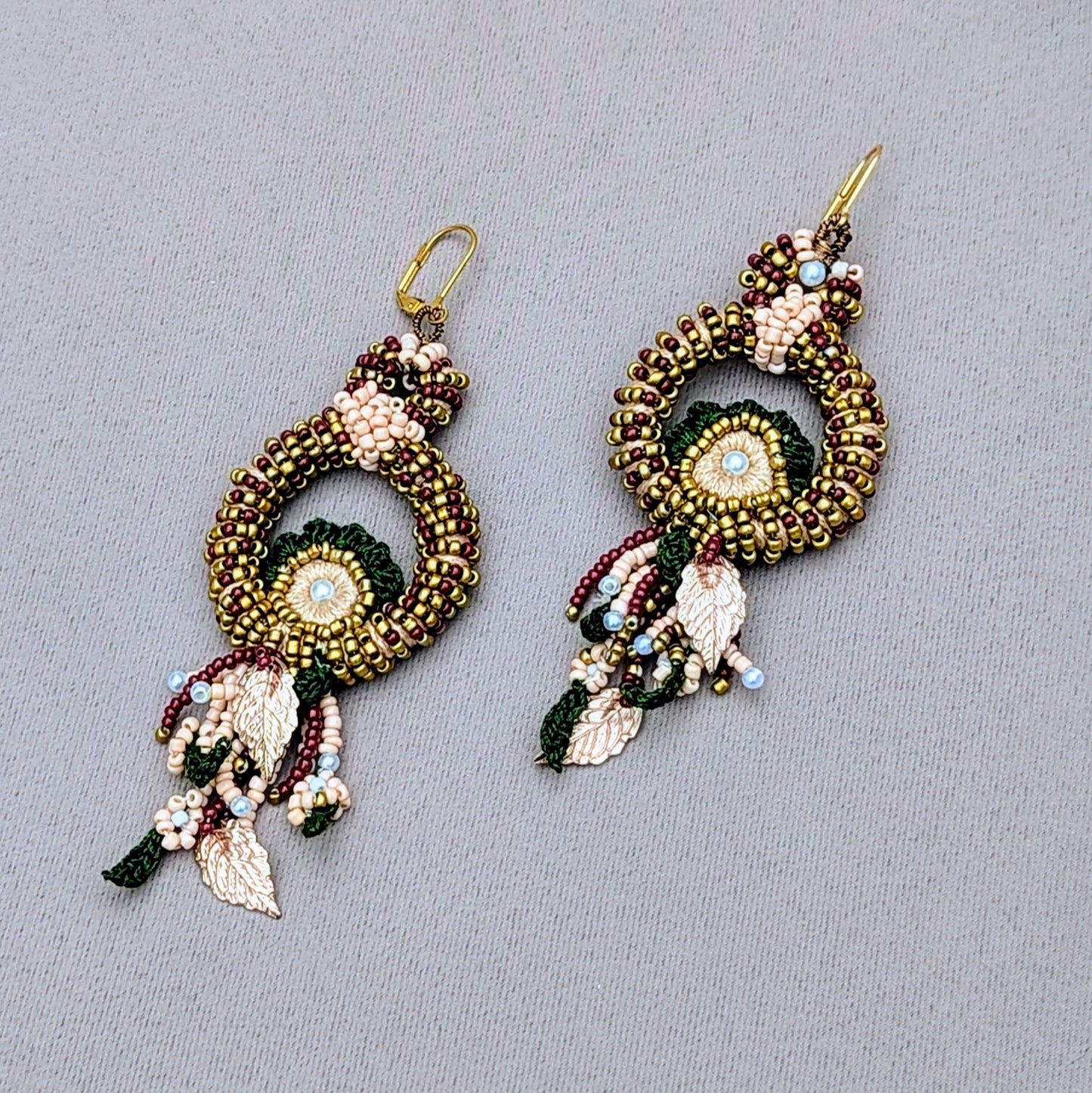 An exceptionally handcrafted pair of unique Indian bridal earrings exclusively available at sustainable UK brand Mayaani Jewellery. Featuring intricate beadwork in red, green and gold, crochet accents and delicate gold leaves for a traditional Indian bridal look with a modern touch of sophistication.