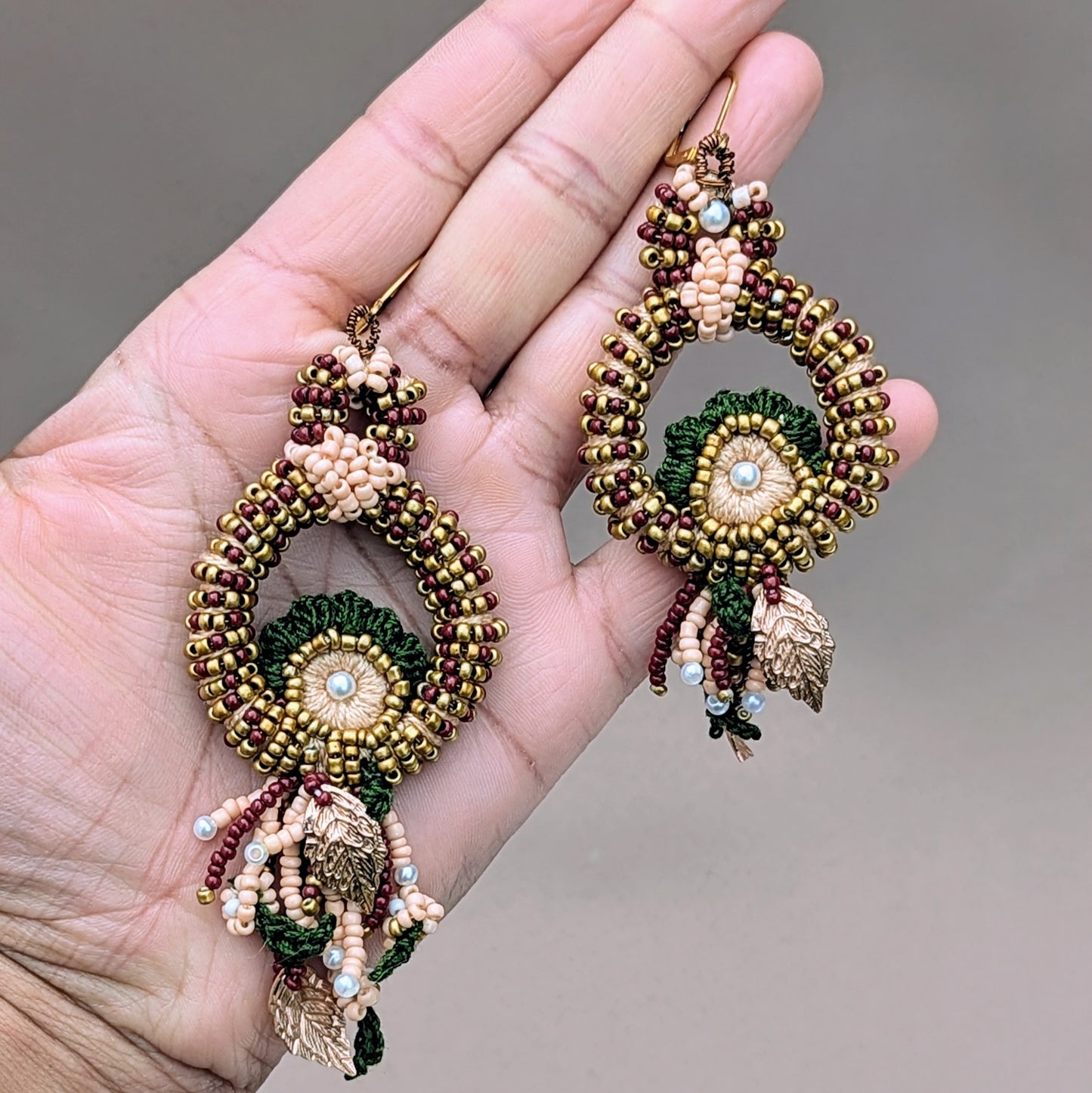 An exquisite pair of handcrafted Indian bridal earrings from sustainable UK brand Mayaani Jewellery showcasing the timeless beauty of traditional red, green and gold hues. Shaped like a peacock, these earrings feature delicate hand bead embroidery, crochet and wire wrapping, all crafted with exceptional attention to detail using only the finest handpicked materials.