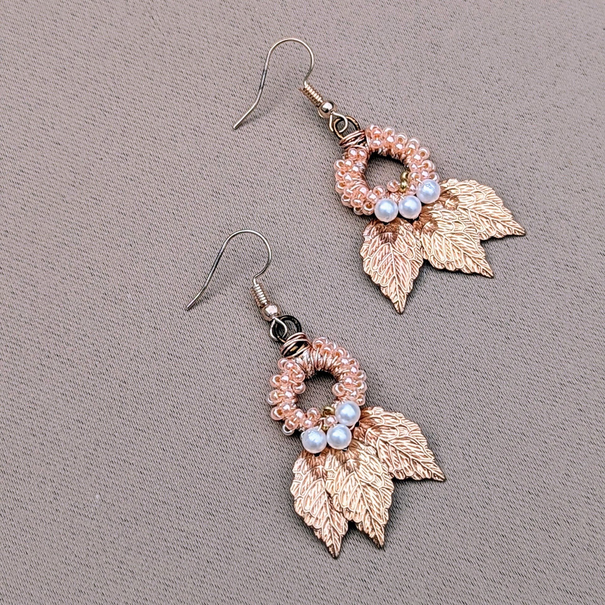 Limited edition Indian Boho earrings by Mayaani Jewellery, featuring gold-plated leaves and handcrafted details. The design blends hand-crocheted peach beads with wire work and seed pearls, reflecting sustainable craftsmanship. Made by a UK brand known for creating eco-conscious accessories, these earrings embrace elegance with a bohemian twist.