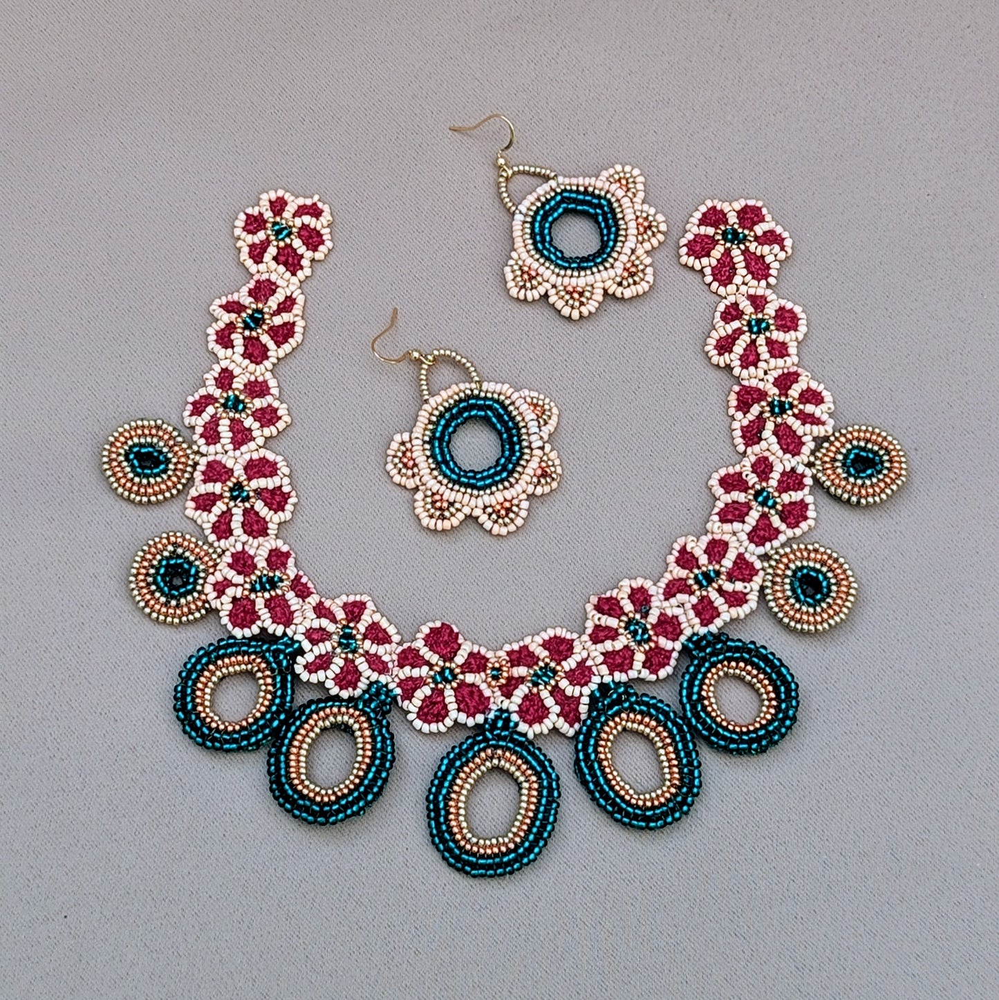 A unique Indian-inspired necklace by sustainable UK brand Mayaani Jewellery, handcrafted with meticulous crochet, beadwork and wirework. The design features rich hues of red, emerald green and peach, complemented by rose gold and gold accents. Floral motifs and striking circular bead pendants bring a fresh, modern twist to traditional Indian bridal jewellery, making this a stand out accessory for special occasions.