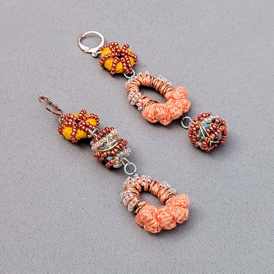 A uniquely handcrafted pair of peach, orange, bronze, and rose gold Indian-style earrings, exclusively from sustainable UK brand Mayaani Jewellery. These earrings showcase signature concept beads created by in-house artisan Megha, made from scraps generated during the jewellery-making process. Celebrating artistry, beauty, and sustainability, they are the perfect choice for weddings and special occasions for the modern eco-conscious woman. Worn daily, they also make a striking sustainable style statement.