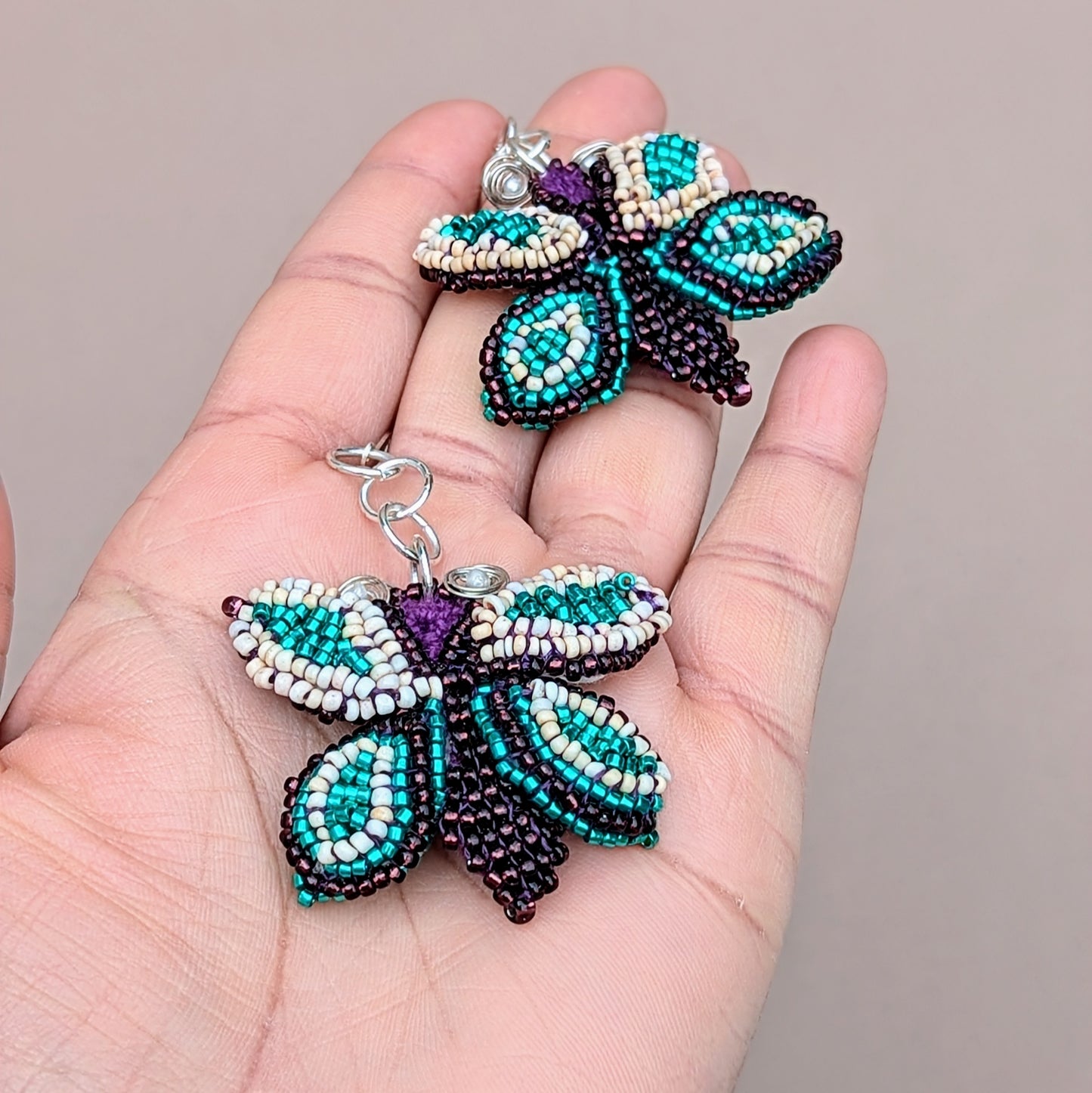 These butterfly statement earrings from Mayaani Jewellery, a sustainable UK brand, are handcrafted with exceptional artistry. Intricate beadwork is showcased on a hand-crocheted base, with wire-wrapped accents and 925 stamped sterling silver lever-back hooks. The rich palette of purple, soft peach, and striking turquoise adds a bold flair, making these earrings a showstopper for any occasion including everyday.