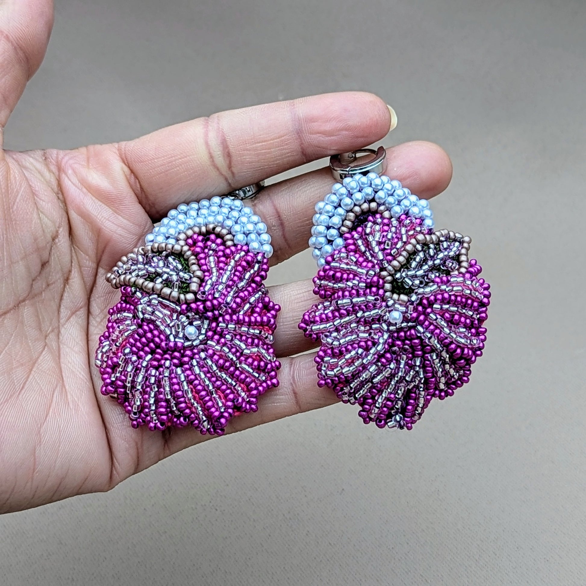 Contemporary style meets traditional craftsmanship in this unique pair of bold eye-catching purple, white and silver Indian earrings exclusively from Mayaani Jewellery UK a sustainable brand. The intricate beadwork and hand crochet fuse together beautifully in a bold daring magenta floral motif featuring silver and ivory pearl accents perfectly complimented by a heavy duty pair of stainless steel closed loop clasps for a modern edge.