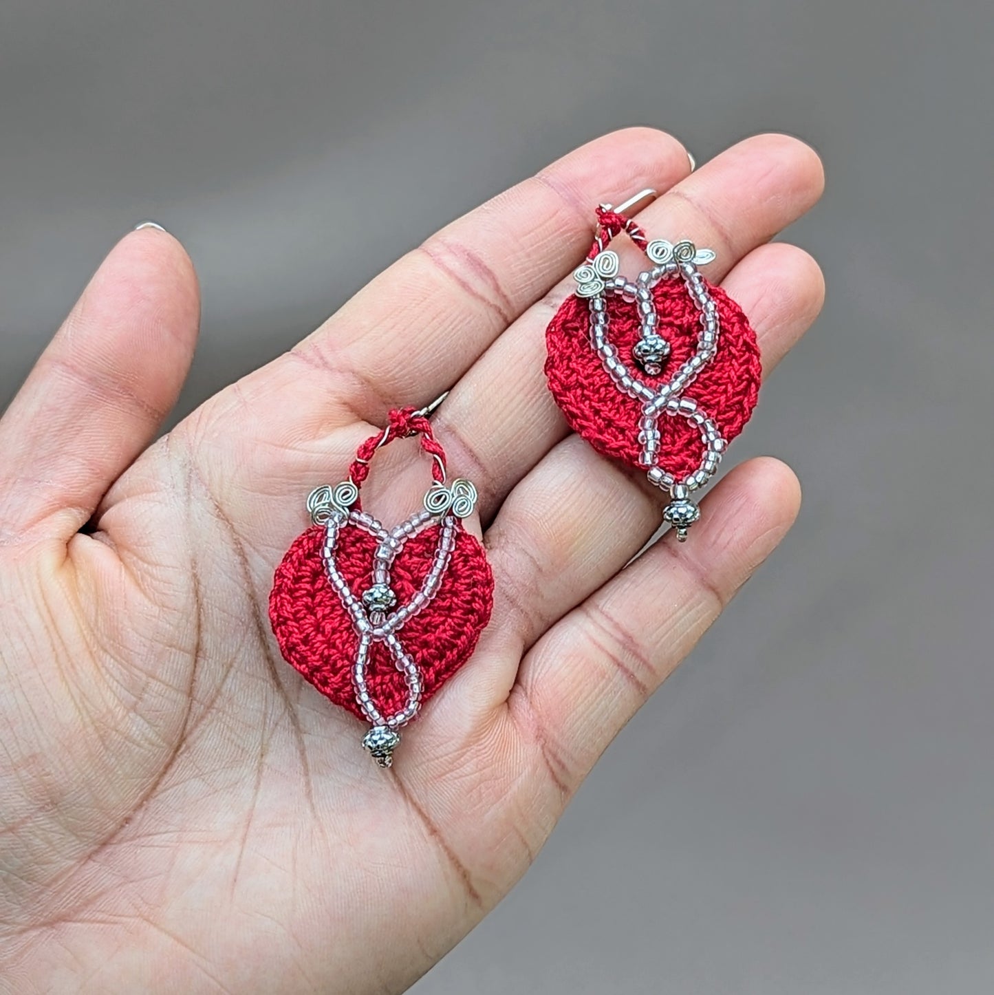 A pair of handcrafted earrings exclusive to sustainable UK brand Mayaani Jewellery, showcasing a vibrant red hand-crocheted design accented with silver bead and silver-plated copper wire detailing. The intricate beadwork, including high quality upcycled beads, adds an elegant touch whilst the 925 stamped sterling silver lever back hooks ensure both style and durability. These earrings combine artisanal craftsmanship with eco-conscious materials offering a unique and ethically made accessory.